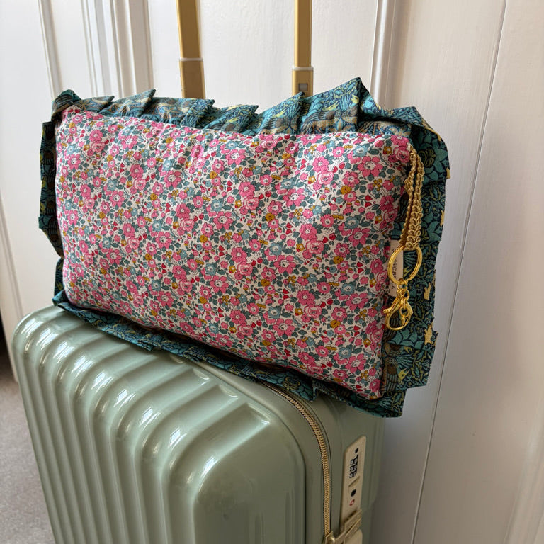 Floral-patterned travel bag on a suitcase with a neutral background