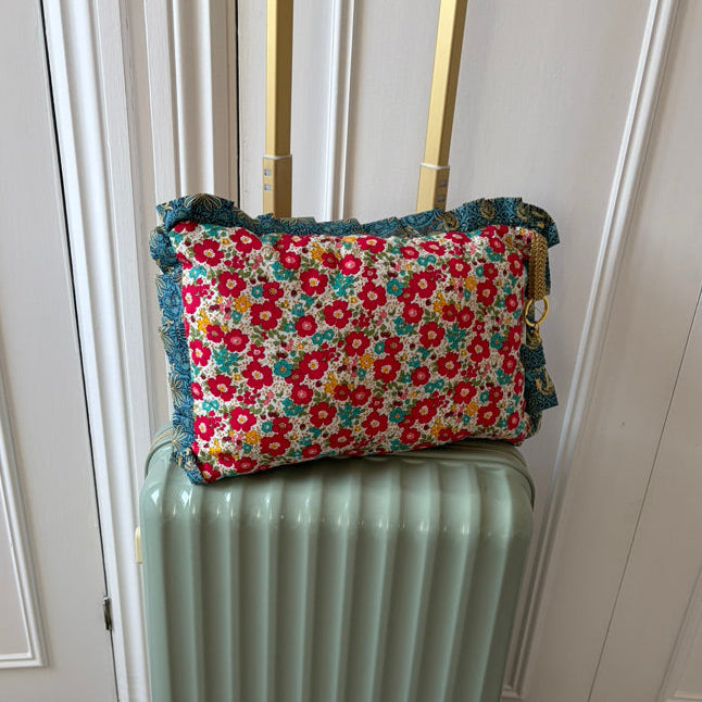 Floral-patterned cushion on top of a light green suitcase against a white door background