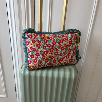 Floral-patterned cushion on top of a light green suitcase against a white door background