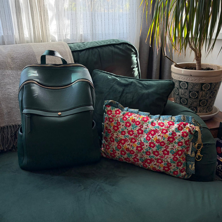 Green backpack and floral cushion on a couch with a plant in the background