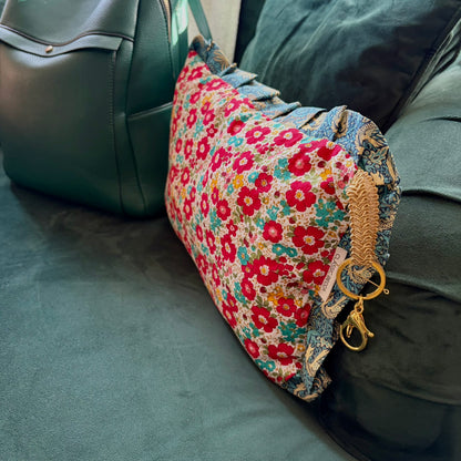 Floral-patterned cushion with a keychain on a green surface