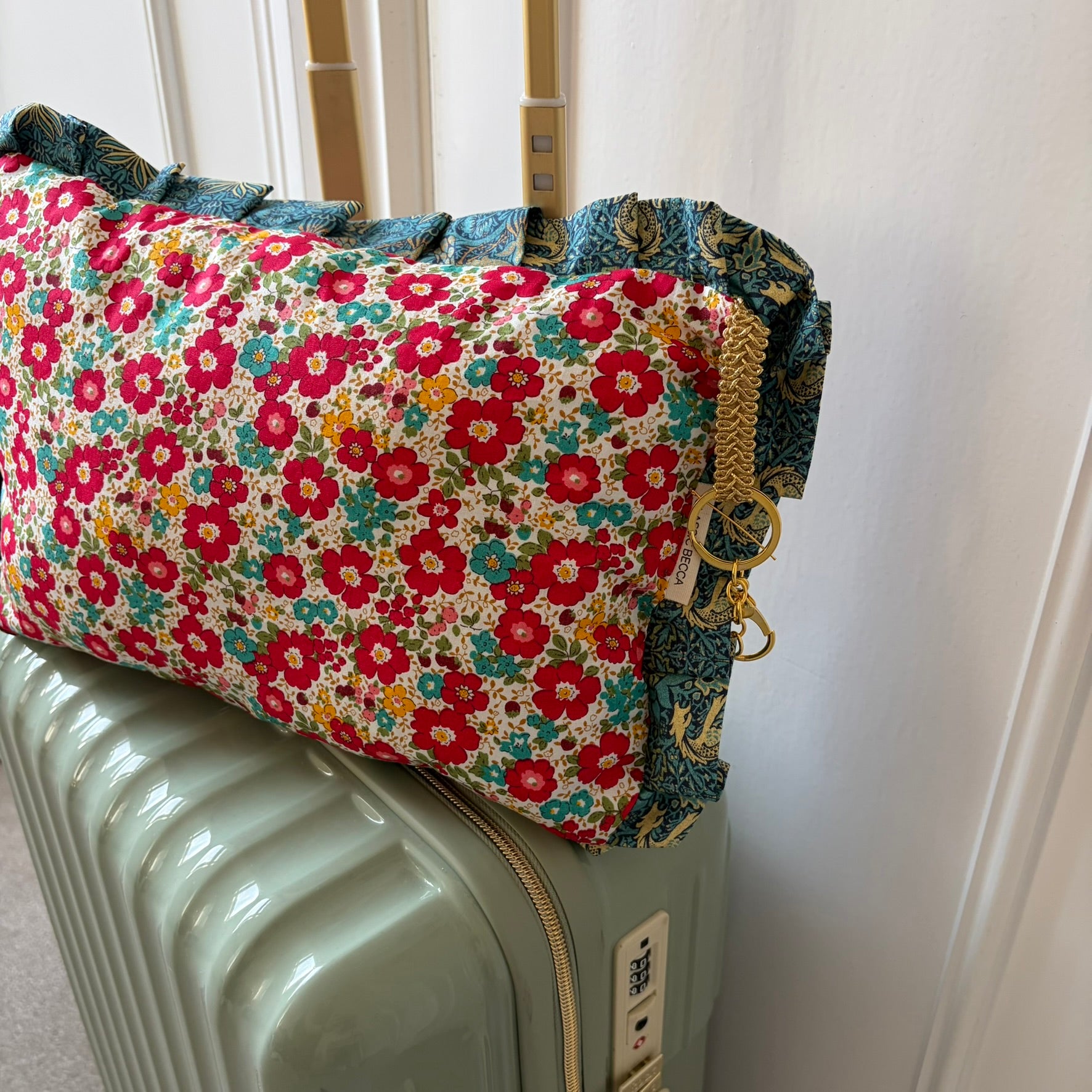 Floral-patterned fabric cushion on a suitcase with a plain background