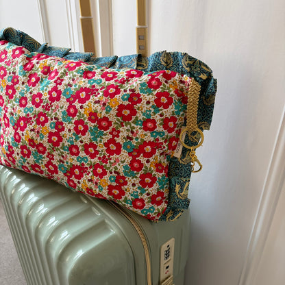 Floral-patterned fabric cushion on a suitcase with a plain background