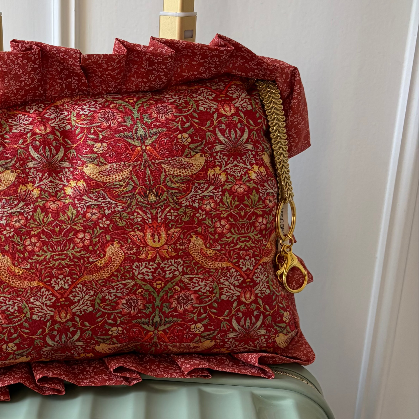 Red patterned pillow with ruffles on a suitcase