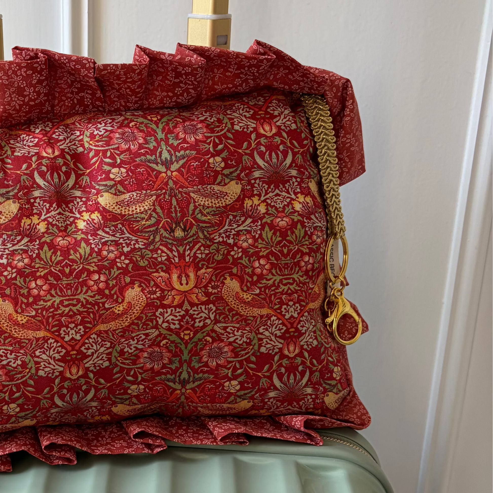 Red patterned pillow with ruffles on a suitcase