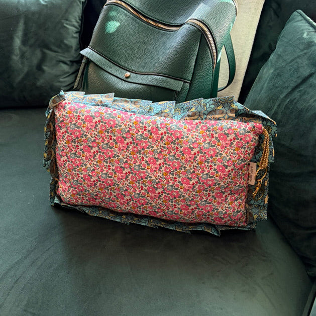 Floral-patterned pillow on a green couch with a green backpack on top