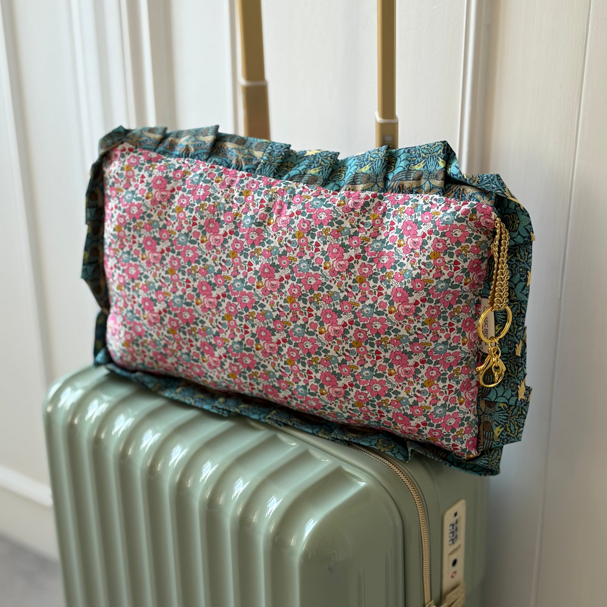 Travel pillow in liberty of london pink fabric on a green suitcase 