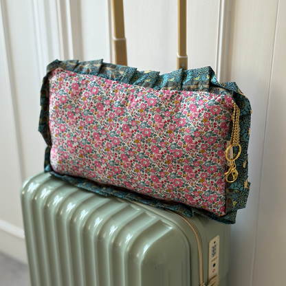 Travel pillow in liberty of london pink fabric on a green suitcase 