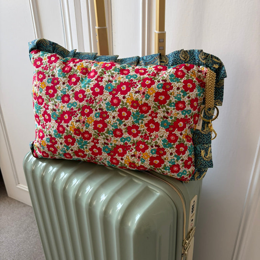 Floral-patterned cushion on a suitcase against a white wall